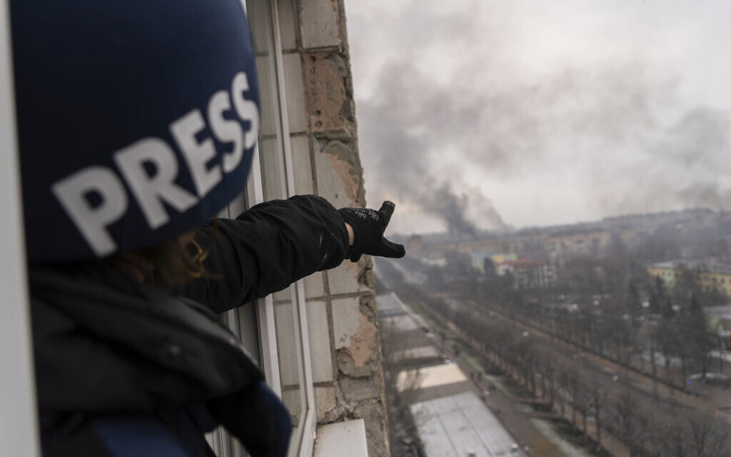 Associated Press photographer Evgeniy Maloletka points at the smoke rising after an airstrike on a maternity hospital, in Mariupol, Ukraine, March 9, 2022. (Mstyslav Chernov/AP)