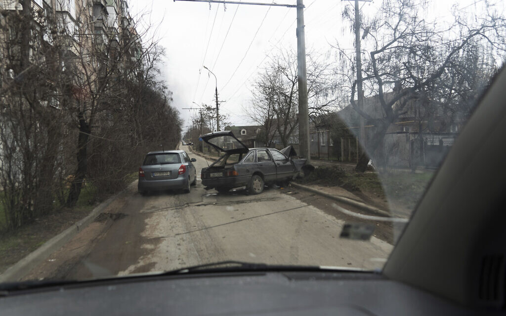 A car escaping from shelling drives past a crashed vehicle in Mariupol, Ukraine, March 4, 2022 (Mstyslav Chernov/AP)