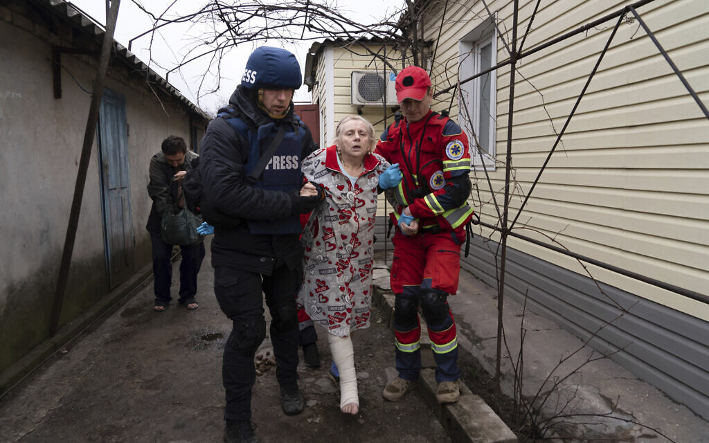 Associated Press photographer Evgeniy Maloletka helps a paramedic to transport a woman injured during shelling in Mariupol, eastern Ukraine, March 2, 2022. (Mstyslav Chernov/AP)