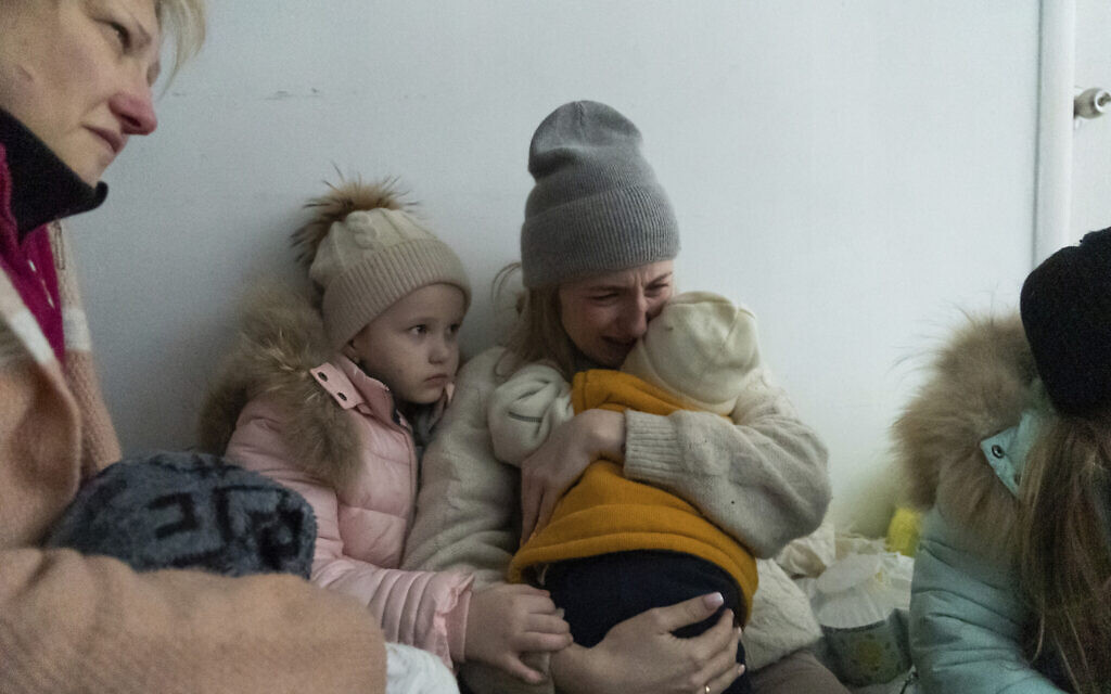 A woman whose husband was killed in the shelling cries on the floor of a corridor in a hospital in Mariupol, eastern Ukraine, March 11, 2022. (Mstyslav Chernov/AP)