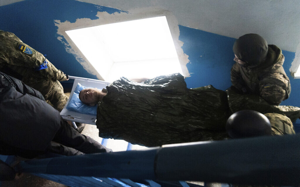 A Ukrainian serviceman and a civilian carry a wounded man who was injured by shelling in a hospital in Mariupol, Ukraine, March 3, 2022. (Mstyslav Chernov/AP)