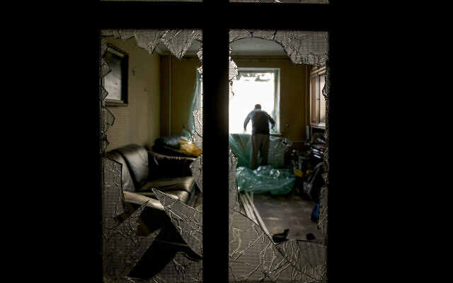 Slava Chikov covers the shattered window of his living room with a plastic sheet in a building damaged by a bombing the previous day in Kyiv, Ukraine, Monday, March 21, 2022. (AP Photo/Vadim Ghirda) Slava Chikov covers the shattered window of his living room with a plastic sheet in a building damaged by a bombing the previous day in Kyiv, Ukraine, Monday, March 21, 2022. (AP Photo/Vadim Ghirda)