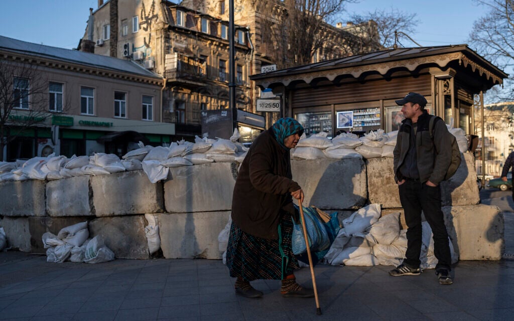 An elderly woman walks pass concrete blocks topped with sandbags at a street in Odesa, southern Ukraine, on Tuesday, March 22, 2022.(AP/Petros Giannakouris)