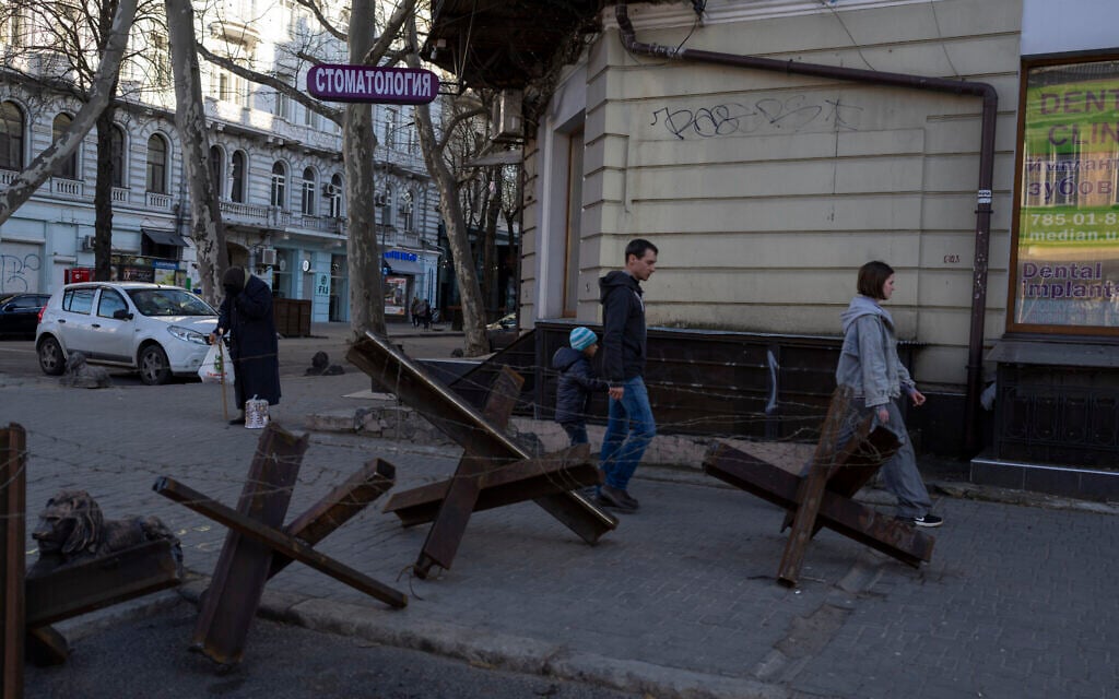 A family walks next to anti- tank barricades in Odesa, southern Ukraine, on Tuesday, March 22, 2022.(AP Photo/Petros Giannakouris)