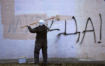 A worker paints over graffiti saying 'Yes to Peace!' on a wall of an apartment building in St. Petersburg, Russia, March 18, 2022. (AP Photo, File)