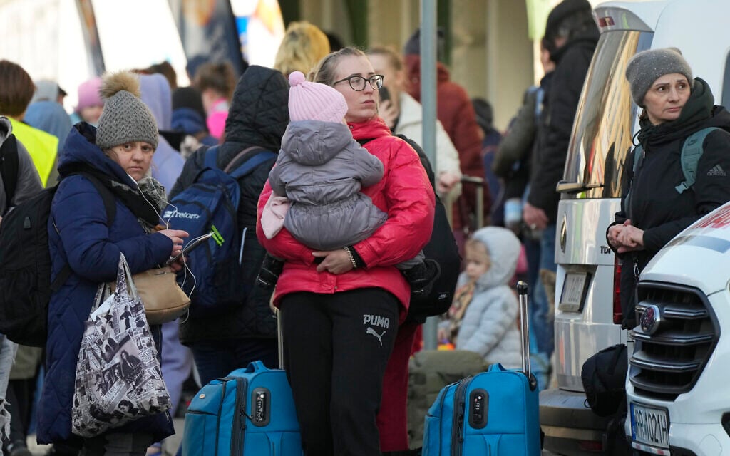 Refugees with children wait for a transport after fleeing the war from neighboring Ukraine at a railway station in Przemysl, Poland, on March 24, 2022. (AP Photo/Sergei Grits)