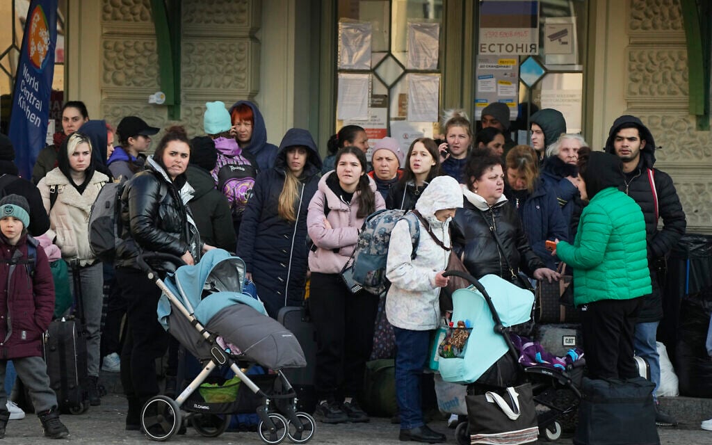 Refugees with children wait for a transport after fleeing the war from neighboring Ukraine at a railway station in Przemysl, Poland, on March 24, 2022. (AP Photo/Sergei Grits)