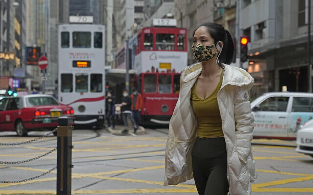 A woman wearing a mask walks across a street in Hong Kong, March 25, 2022. (AP Photo/Kin Cheung) A woman wearing a mask walks across a street in Hong Kong, March 25, 2022. (AP Photo/Kin Cheung)