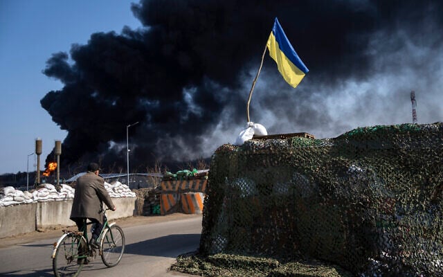 A man rides a bicycle as black smoke rises from a fuel storage of the Ukrainian army following a Russian attack, on the outskirts of Kyiv, Ukraine, Friday, March 25, 2022. (AP/Rodrigo Abd) A man rides a bicycle as black smoke rises from a fuel storage of the Ukrainian army following a Russian attack, on the outskirts of Kyiv, Ukraine, Friday, March 25, 2022. (AP/Rodrigo Abd)