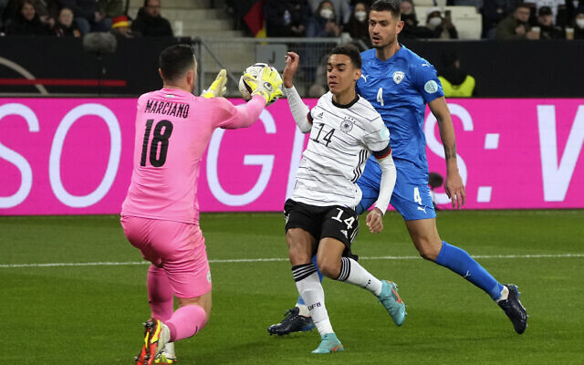 Israel's goalkeeper Ofir Marciano, left, makes a save in front of Germany's Jamal Musiala, center, during the international friendly soccer match between Germany and Israel in Sinsheim, Germany, March 26, 2022. (Michael Probst/AP) Israel's goalkeeper Ofir Marciano, left, makes a save in front of Germany's Jamal Musiala, center, during the international friendly soccer match between Germany and Israel in Sinsheim, Germany, March 26, 2022. (Michael Probst/AP)
