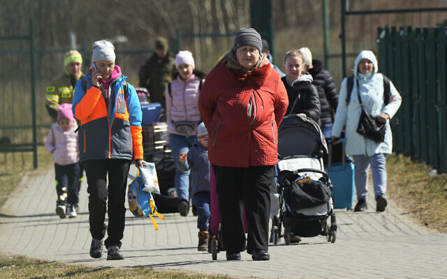 Refugees walk at the border crossing in Medyka, southeastern Poland, after fleeing the war from neighboring Ukraine, March 27, 2022. (AP Photo/Sergei Grits)
