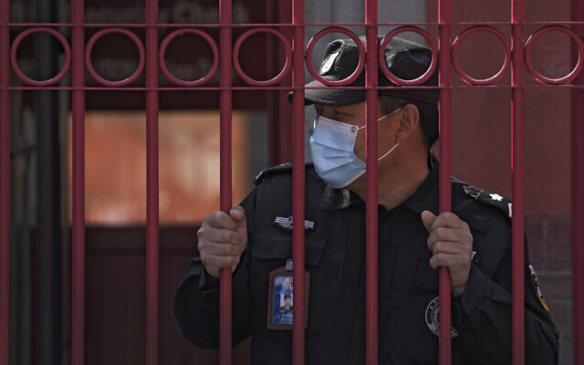 A security guard wearing a mask to help protect from the coronavirus stands behind a fence, Monday, March 28, 2022, in Beijing. China began its largest lockdown in two years Monday to conduct mass testing and control a growing outbreak in its largest city of Shanghai as questions are raised about the economic toll of the nation's "zero-COVID" strategy. (AP Photo/Andy Wong) A security guard wearing a mask to help protect from the coronavirus stands behind a fence, Monday, March 28, 2022, in Beijing. China began its largest lockdown in two years Monday to conduct mass testing and control a growing outbreak in its largest city of Shanghai as questions are raised about the economic toll of the nation's "zero-COVID" strategy. (AP Photo/Andy Wong)