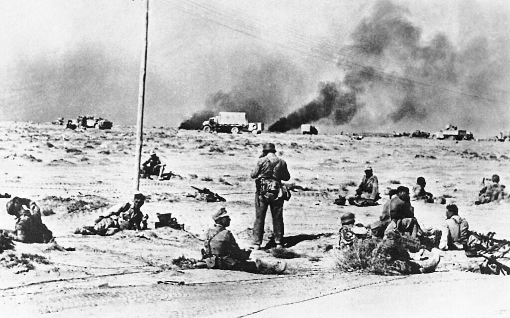German infantry sit on the desert sands during a rest period as smoke pours from shelled positions around Tobruk on July 17, 1942. (AP Photo)
