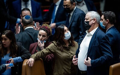 Defense Minister Benny Gantz speaks with opposition MK Miri Regev, with coalition whip MK Idit Silman (L) looking on, during a Knesset plenum session, February 28, 2022. (Yonatan Sindel/Flash90)