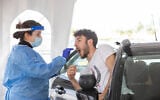 A technician collects a nasal swab sample for COVID-19 at the coronavirus lab, at the Ben Gurion International Airport on March 2, 2022. (Yossi Aloni/Flash90)