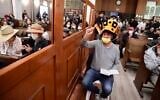 People read from Megillat Esther (the Story of Esther) during the Jewish holiday of Purim, at the Great Synagogue in Tel Aviv, on March 16, 2022. (Avshalom Sassoni/Flash90)