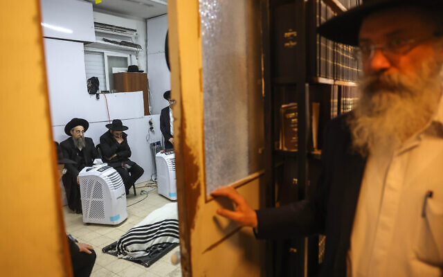 Family and relatives pray as they gather around the body of Rabbi Chaim Kanievsky, Bnei Brak, March 20, 2022 (Yonatan Sindel/ Flash90)