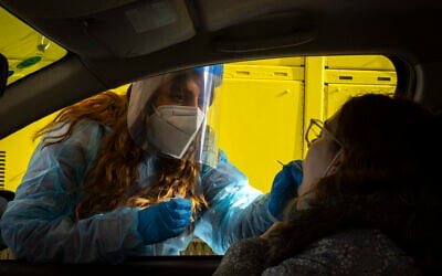 A Magen David worker takes a swab sample at a COVID-19 drive-thru testing site in Jerusalem, on March 22, 2022. (Olivier Fitoussi/Flash90) A Magen David worker takes a swab sample at a COVID-19 drive-thru testing site in Jerusalem, on March 22, 2022. (Olivier Fitoussi/Flash90)