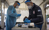 Magen David worker take a COVID-19 rapid antigen test from Israelis, at a Magen David Adom drive through complex in Jerusalem, March 22, 2022. (Olivier Fitoussi/Flash90)