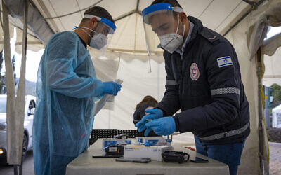 Magen David worker take a COVID-19 rapid antigen test from Israelis, at a Magen David Adom drive through complex in Jerusalem, March 22, 2022. (Olivier Fitoussi/Flash90)