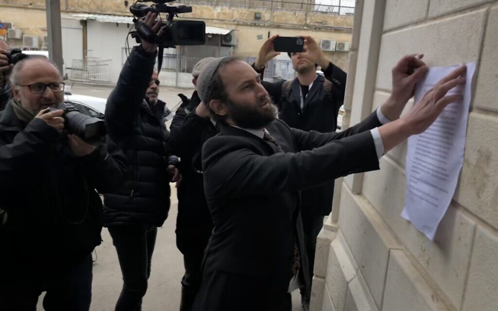 Rabbi Yonatan Neril posts an interfaith letter against the war in Ukraine to Russian Orthodox Patriarch Kirill on the walls of Jerusalem’s Holy Trinity Cathedral, March 21, 2022 (Lazar Berman/Times of Israel)