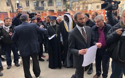 Rabbi Yonatan Neril posts an interfaith letter against the war in Ukraine to Russian Orthodox Patriarch Kirill on the walls of Jerusalem’s Holy Trinity Cathedral, March 21, 2022. (Lazar Berman/Times of Israel)