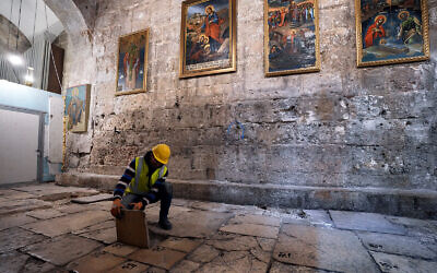 A member of the restoration team removes a stone from the floor of the Church of the Holy Sepulchre, where many Christians believe Jesus was crucified, buried and rose from the dead, in the Old City of Jerusalem, Thursday, March 17, 2022. (AP Photo/Mahmoud Illean)
