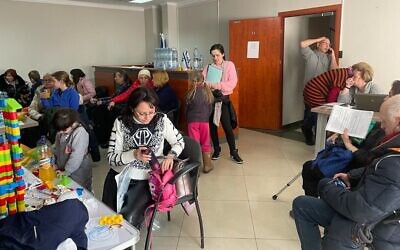 Jewish Agency emissary Rafi Heltzer (grey sweatshirt, top right) handles calls in the doorway to the lobby Israel's honorary consulate in Lviv, Ukraine, March 15, 2022. (Carrie Keller-Lynn/The Times of Israel)