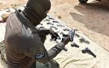 A Magen unit police officer inspects weapons seized by Israeli security forces during a gun-smuggling attempt along the border with Jordan on March 11, 2022. (Israel Police)