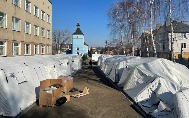 Ukrainian workers construct tents for the Israeli field hospital being established in Mostyska, Ukraine. on March 18, 2022. (Carrie Keller-Lynn/The Times of Israel)