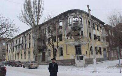 Rabbi Menachem Mendel Cohen stands outside the burned out building that served as local police headquarters in Mariupol. (Chabad.org)