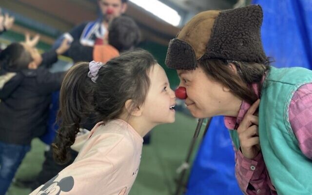 Shemesh (Smadar Harpak), who works at the Sourasky Medical Center in Tel Aviv, jokes with a Ukrainian refugee child at a camp established at the International Exhibition Centre MoldExpo in Chisinau, Moldova, March 9, 2022. (Hila Pe'er)