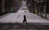 People walk along an empty road during curfew, in Kyiv, Ukraine, on Tuesday, March 1, 2022. (AP Photo/Emilio Morenatti)
