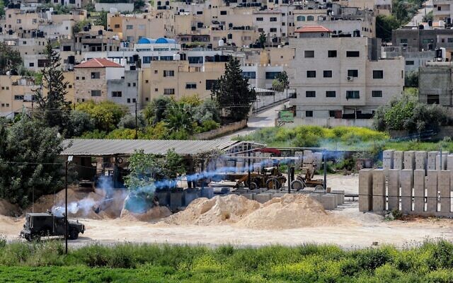 Tear gas canisters are fired from an Israeli military vehicle near the Palestinian refugee camp of Jenin in the West Bank during a raid on a terrorist's home on April 9, 2022 (JAAFAR ASHTIYEH / AFP)