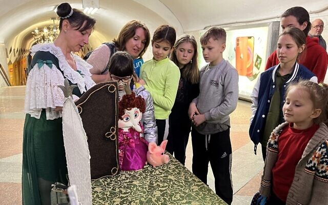 Children watch puppeteer Oleksandra Shlykova (L) as she performs at the metro stations of Kharkiv, eastern Ukraine, on April 16, 2022. (Maryke Vermaak/AFP)