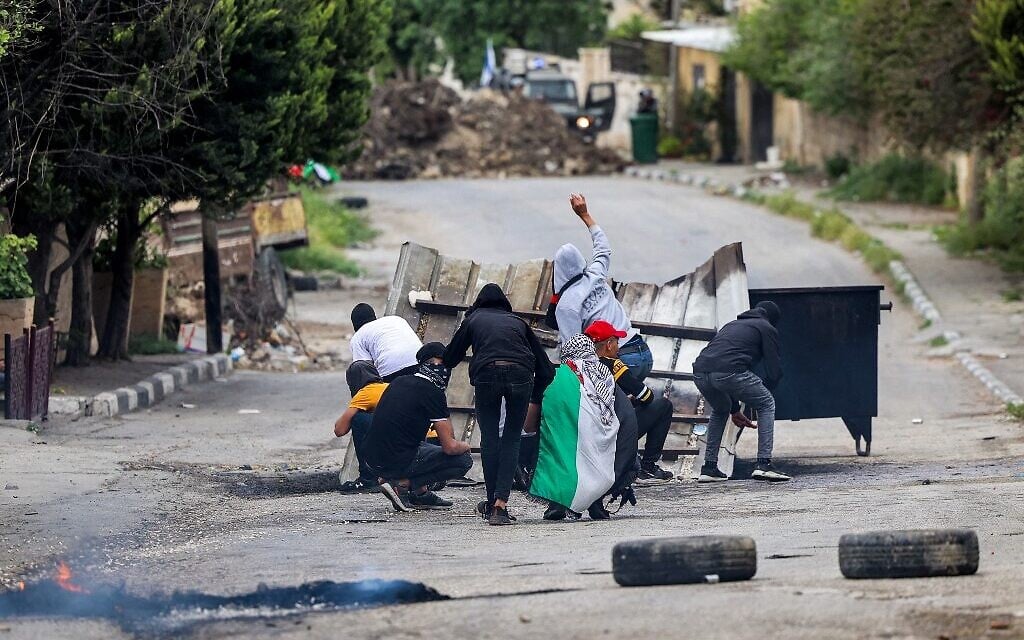 Palestinians throw stones at Israeli forces in the West Bank village of Burqa during clashes to protest a march by Israelis to the wildcat settlement outpost of Homesh on April 19, 2022. (JAAFAR ASHTIYEH / AFP)