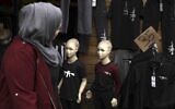 A woman looks at T-shirts with M-16 rifles printed on them, displayed in a shop window at a market in the West Bank city of Ramallah, on April 20, 2022.  (Abbas Momani/AFP)
