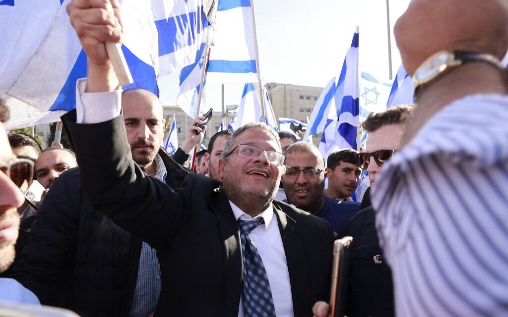 MK Itamar Ben Gvir, leader of the far-right Otzma Yehudit (Jewish Power) faction of the Religious Zionist party, raises an Israeli flag in Safra Square in Jerusalem on April 20, 2022, at the start of a planned nationalist march. (Menahem Kahana / AFP) MK Itamar Ben Gvir, leader of the far-right Otzma Yehudit (Jewish Power) faction of the Religious Zionist party, raises an Israeli flag in Safra Square in Jerusalem on April 20, 2022, at the start of a planned nationalist march. (Menahem Kahana / AFP)