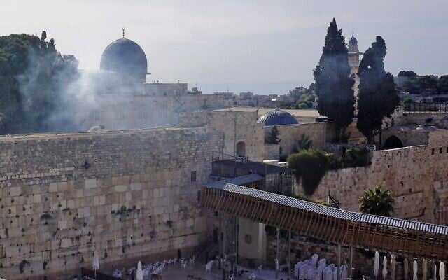 The Western Wall in Old Jerusalem with smoke billowing from a burning tree in the courtyard of the Temple Mount above, during clashes between Palestinians and Israeli police on April 22, 2022. (Claire Gounon/AFP)