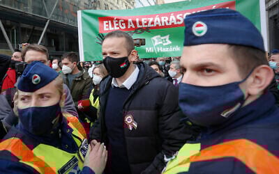 Laszlo Toroczkai, center, head of the Our Homeland Movement, is flanked by police officers during a protest in Budapest, Hungary, Monday, March 15, 2021. (AP Photo/Laszlo Balogh)