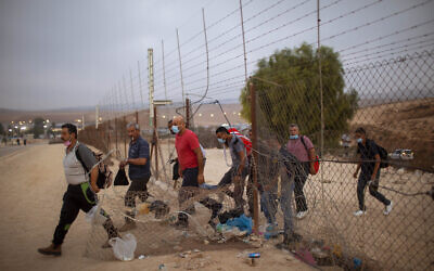 In this September 6, 2020 photo, Palestinian laborers cross illegally into Israel from the West Bank through an opening in a fence, south of the West Bank town of Hebron. (AP Photo/Oded Balilty, File)