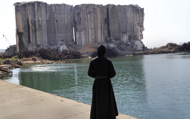 A priest looks towards the towering grain silos, that were gutted in the massive explosion in Beirut in August 2020, on August 4, 2021. (AP Photo/Hussein Malla) A priest looks towards the towering grain silos, that were gutted in the massive explosion in Beirut in August 2020, on August 4, 2021. (AP Photo/Hussein Malla)