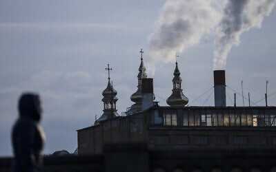 A woman walks with a power plant in the background, in Vinnytsia, Ukraine, on March 16, 2022. (AP Photo/Rodrigo Abd, File)