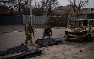 Ukrainian soldiers recover the remains of four killed civilians from inside a charred vehicle in Bucha, outskirts of Kyiv, Ukraine, on April 5, 2022. (AP Photo/Felipe Dana)