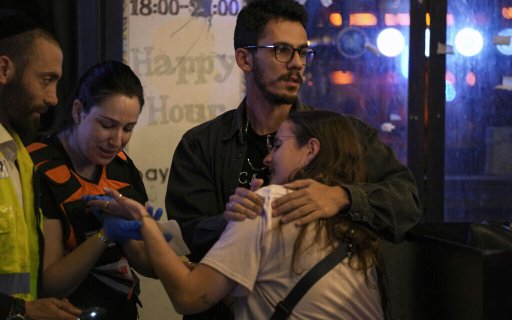 A woman is treated near the scene of a terror attack in Tel Aviv, Israel, Thursday, April 7, 2022. Israeli health officials say two people were killed and at least eight others wounded in a shooting in central Tel Aviv.  (AP Photo/Ariel Schalit)