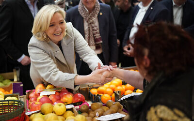 French far-right leader Marine Le Pen shakes hands to a fruits seller as she tours a food market in Narbonne, southern France, on April 8, 2022. (AP Photo/Joan Mateu Parra)