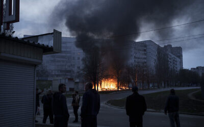 Residents stand outside their apartments as shops burn after a Russian attack in Kharkiv, Ukraine, Monday, April 11, 2022. (AP Photo/Felipe Dana)