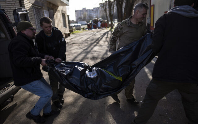 Volunteers carry the body of a man killed during the war to a refrigerated container in Bucha, in the outskirts of Kyiv, Ukraine, Thursday April 14, 2022. (AP Photo/Rodrigo Abd) Volunteers carry the body of a man killed during the war to a refrigerated container in Bucha, in the outskirts of Kyiv, Ukraine, Thursday April 14, 2022. (AP Photo/Rodrigo Abd)
