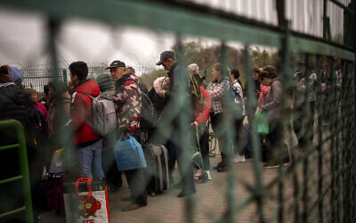 Ukrainians carrying their belongings line up to enter in Poland as they flee their country crossing the Medyka border, Friday, April 15, 2022. (AP/Emilio Morenatti)