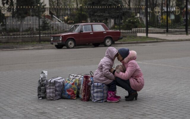 A mother hugs her daughter as they wait for a bus to flee from Sloviansk city, in Donetsk district, to travel to Rivne , western Ukraine, on April 16, 2022. (AP Photo/Petros Giannakouris)